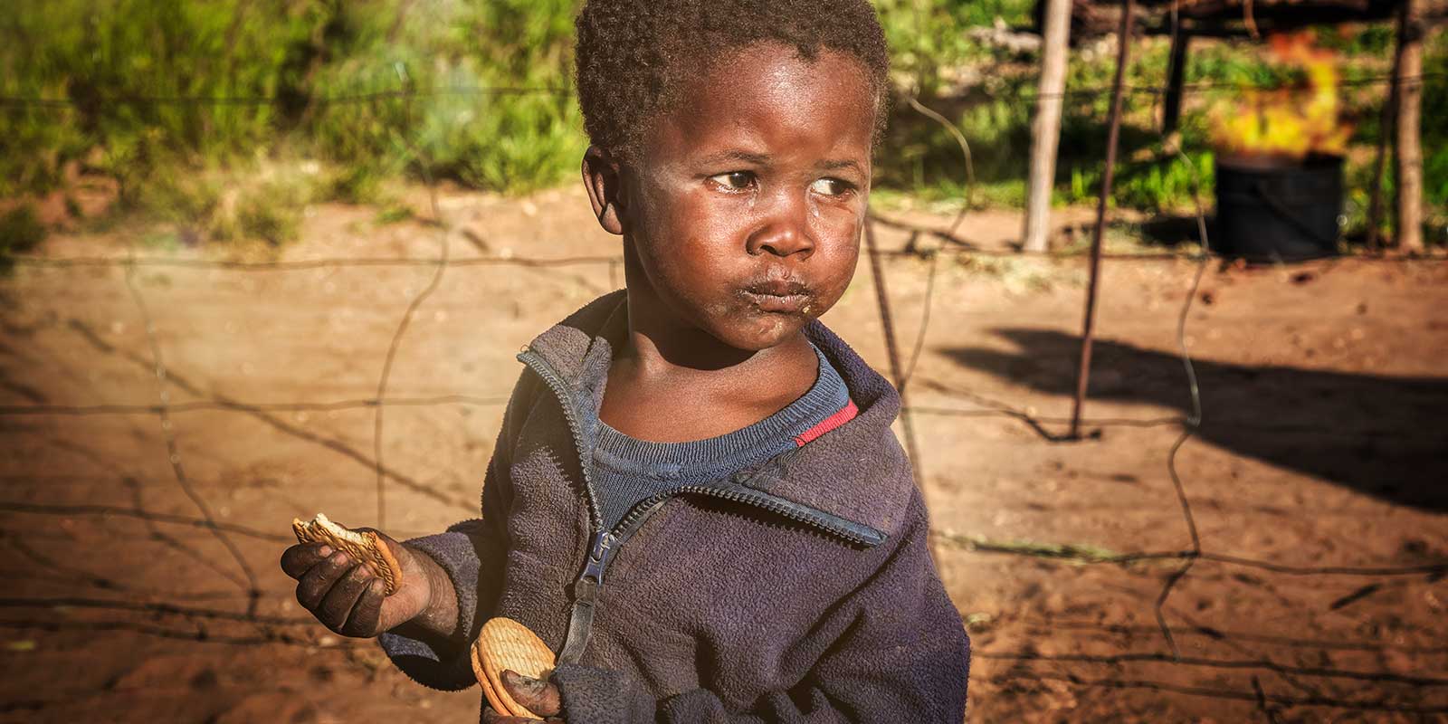 Young boy in Africa looking tired eating cookies